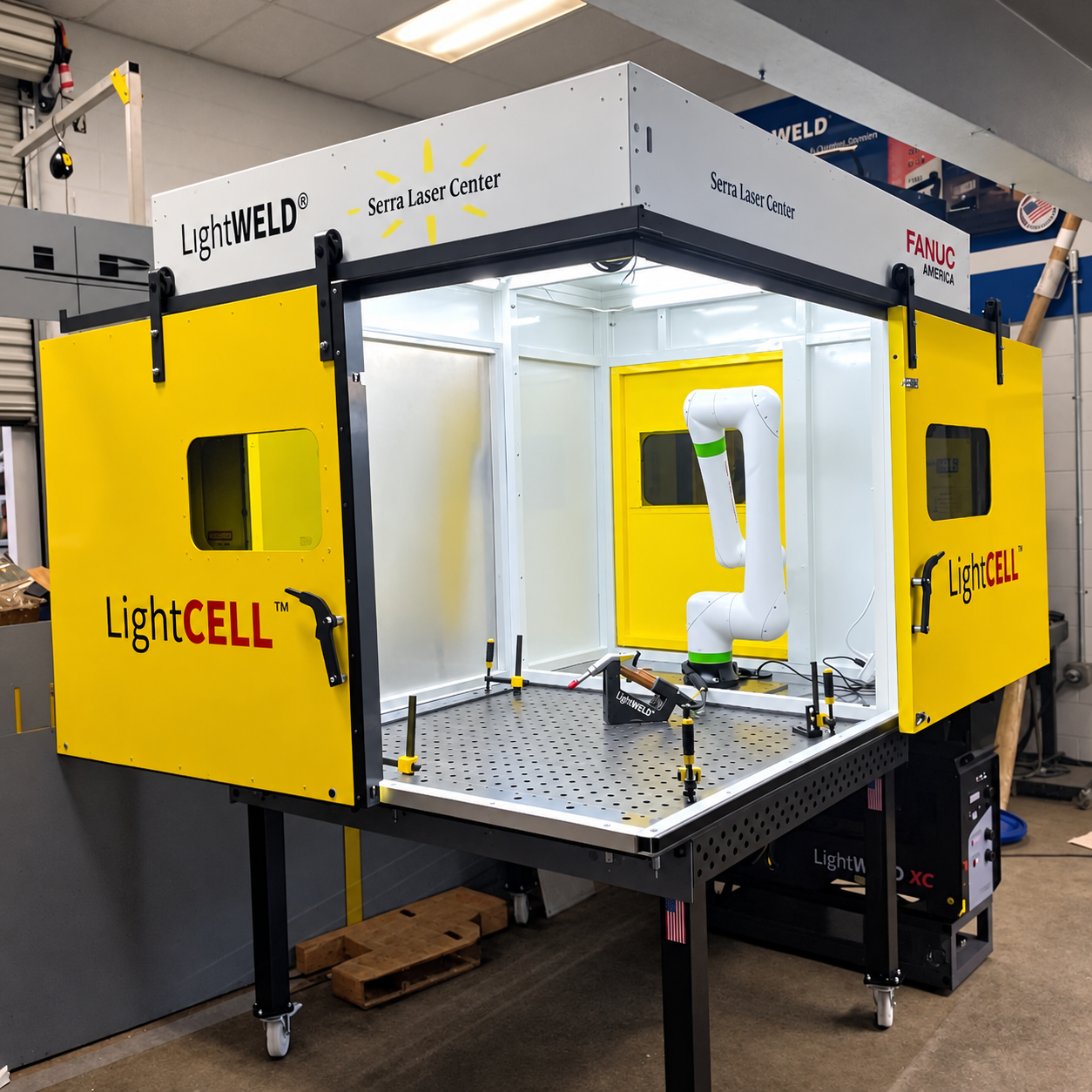 Table-mounted LightCELL enclosure with sliding yellow doors open around a FANUC CRX